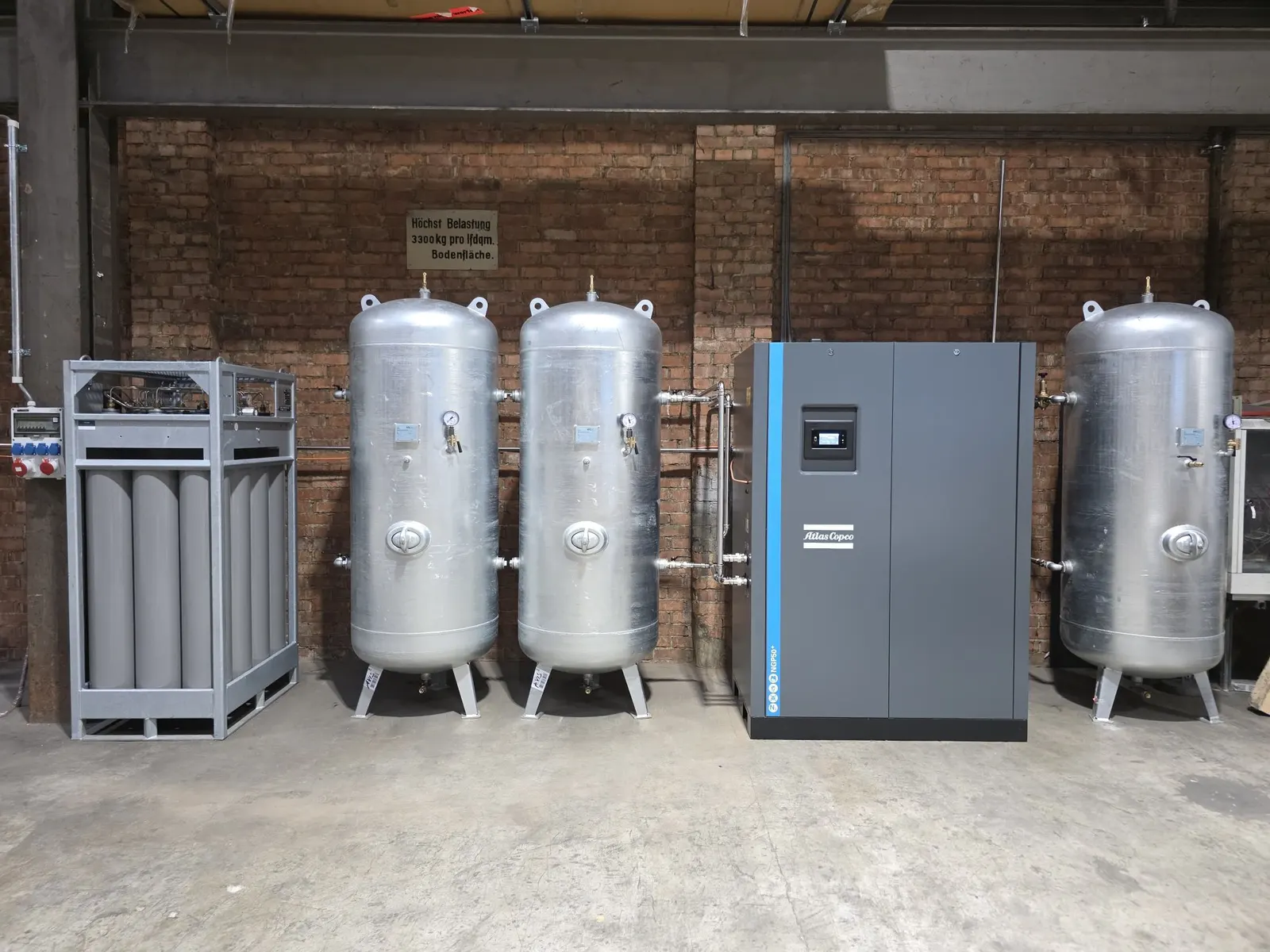 Atlas Copco NGP 50+ Stickstoffgenerator mit drei Behältern und Flaschenbündel vor einer Backsteinwand